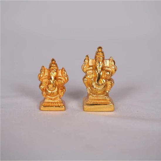 Two gold-colored Ganesh statues on a gray background