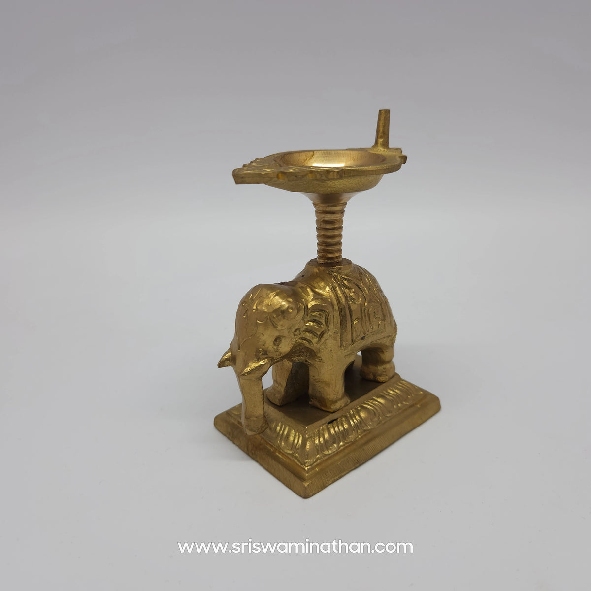 Front angular three-quarter view of the pure brass elephant lamp focusing on the majestic facial details and wick holder