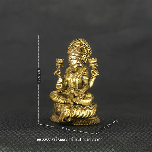 Three-quarter front left perspective view of the 4.5cm brass Lakshmi statue on an elephant head pedestal next to an altar ruler to demonstrate the compact micro scale.