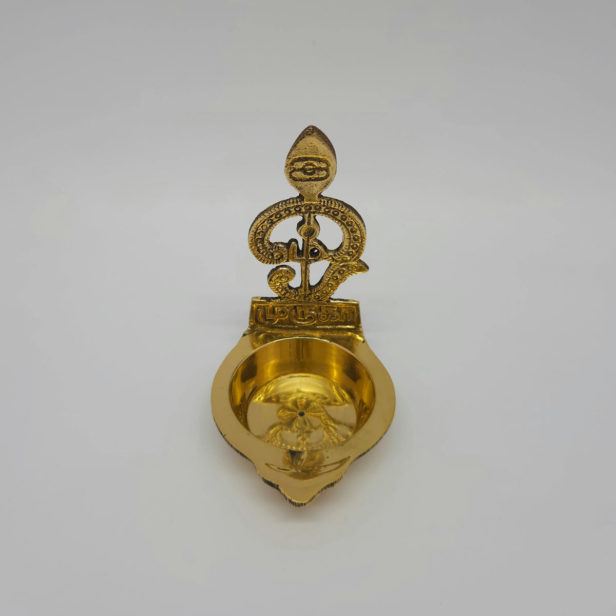 High angle top-down view looking directly into the smooth brass Murugan diya basin highlighting the single-spout wick nose projection.
