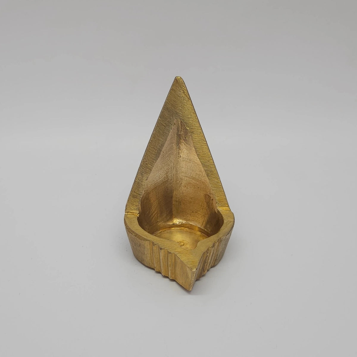 Alternative front profile view of the fifteen milliliter capacity brass mada vilakku highlighting the natural bright white light glints reflecting off the hand polished surface