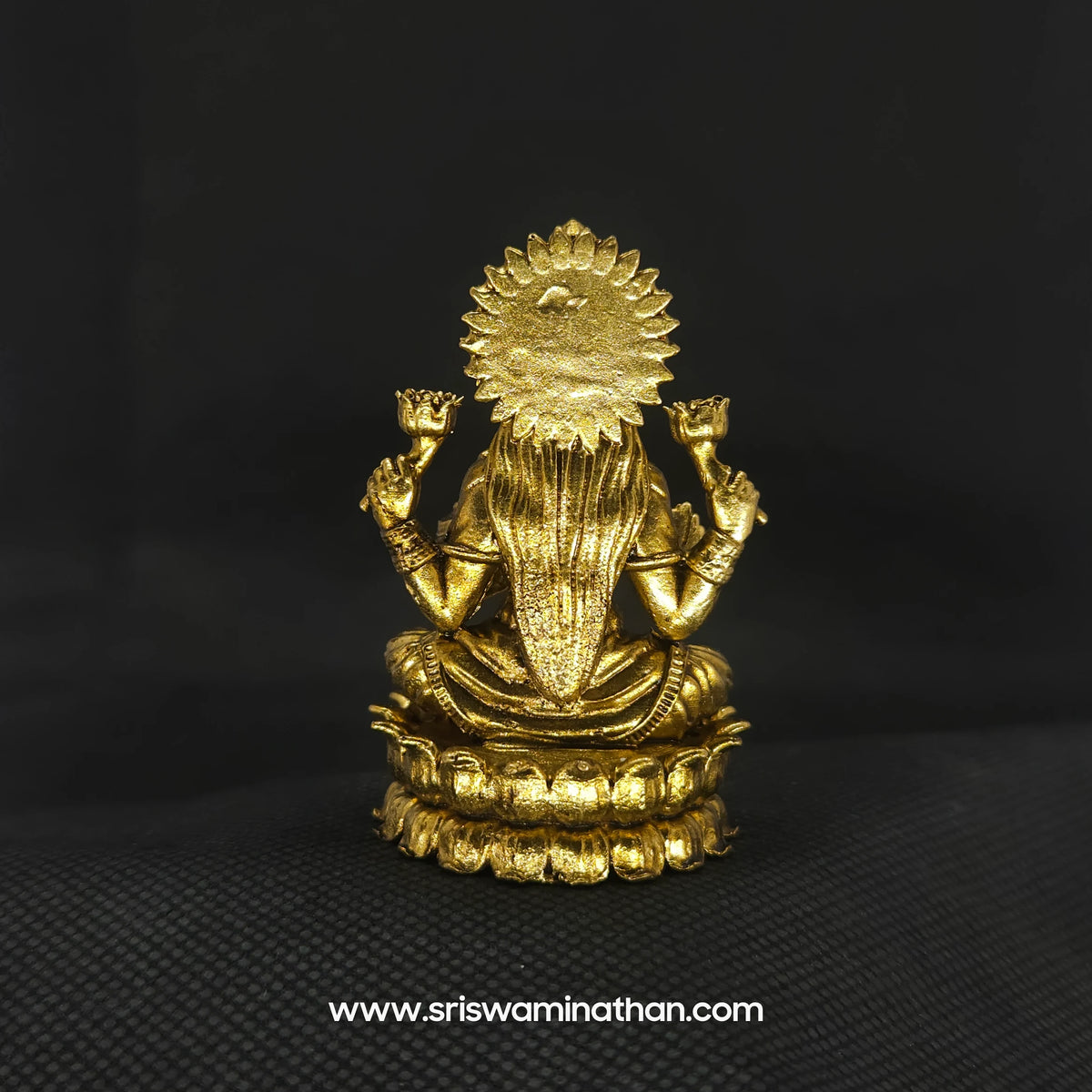 Direct straight back view of the solid brass seated Lakshmi statue with Akshaya Patram demonstrating the detailed rear surface of the sunburst halo crown and back hair arrangement.
