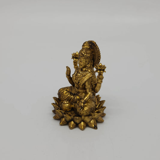 Three-quarter front right perspective view of the two and a half inch brass Lakshmi statue in her real form showcasing the beautifully chiseled lotus buds held in her upper hands.