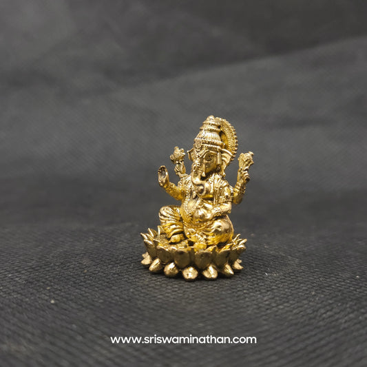 Three-quarter front right perspective view of the one inch brass Ganesha statue showcasing his prominent fat abdomen, the detailed modak, and Mooshikan seated on the round lotus edge.