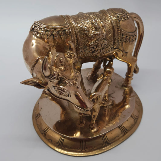 Sri Swaminathan and Co handcraft style Panchaloha Kamadhenu cow and calf statue 16cm height 45 degree left pose corner view highlighting the suckling calf and ornate facial jewelry
