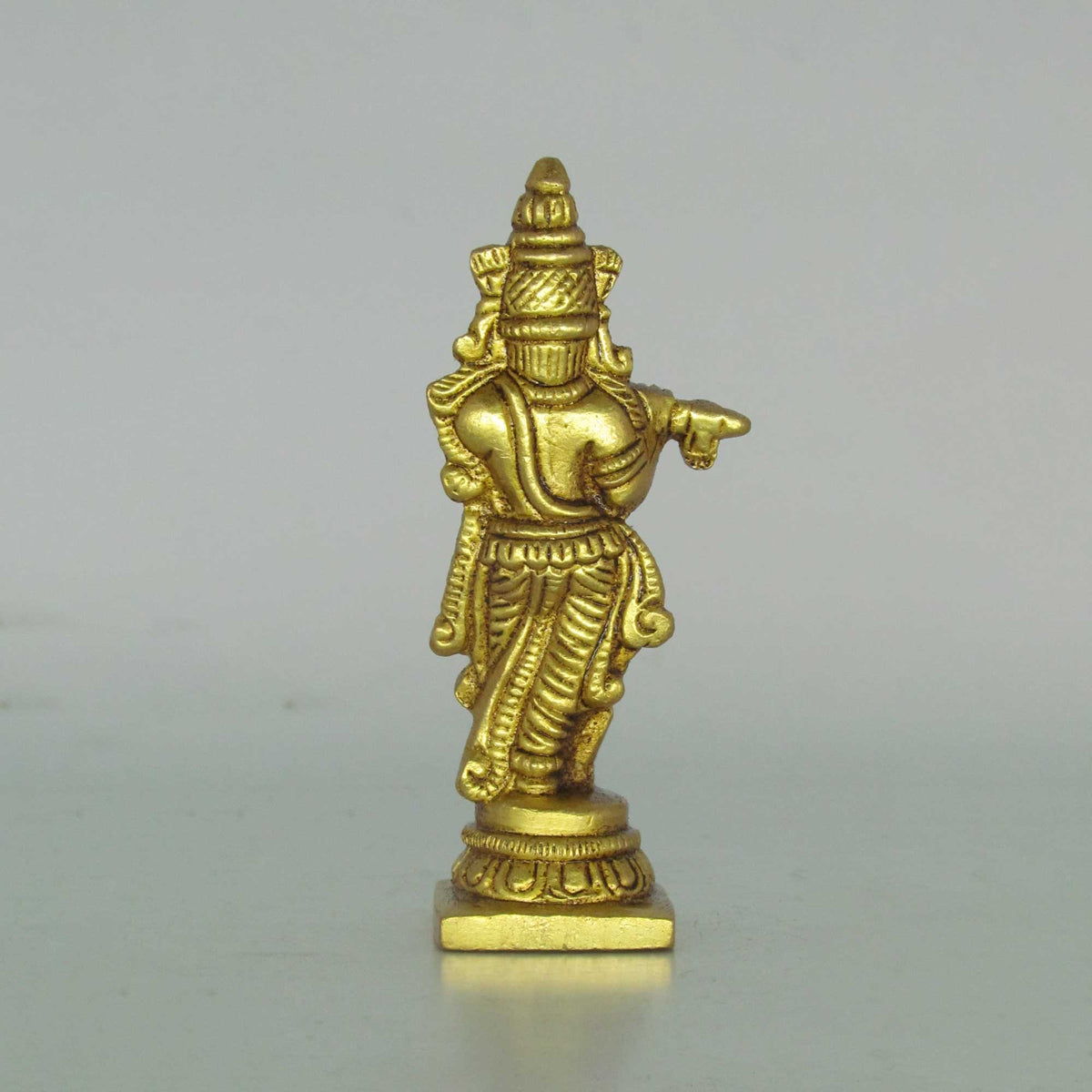 Direct rear back view of a solid brass fluting Krishna statue highlighting the detailed hair carvings, sash lines, and square base.