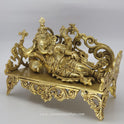 Decorative gold sculpture of a reclining figure on a gray background
