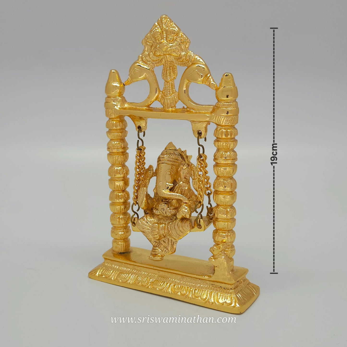 Side view of brass Ganesha statue seated on decorative swing