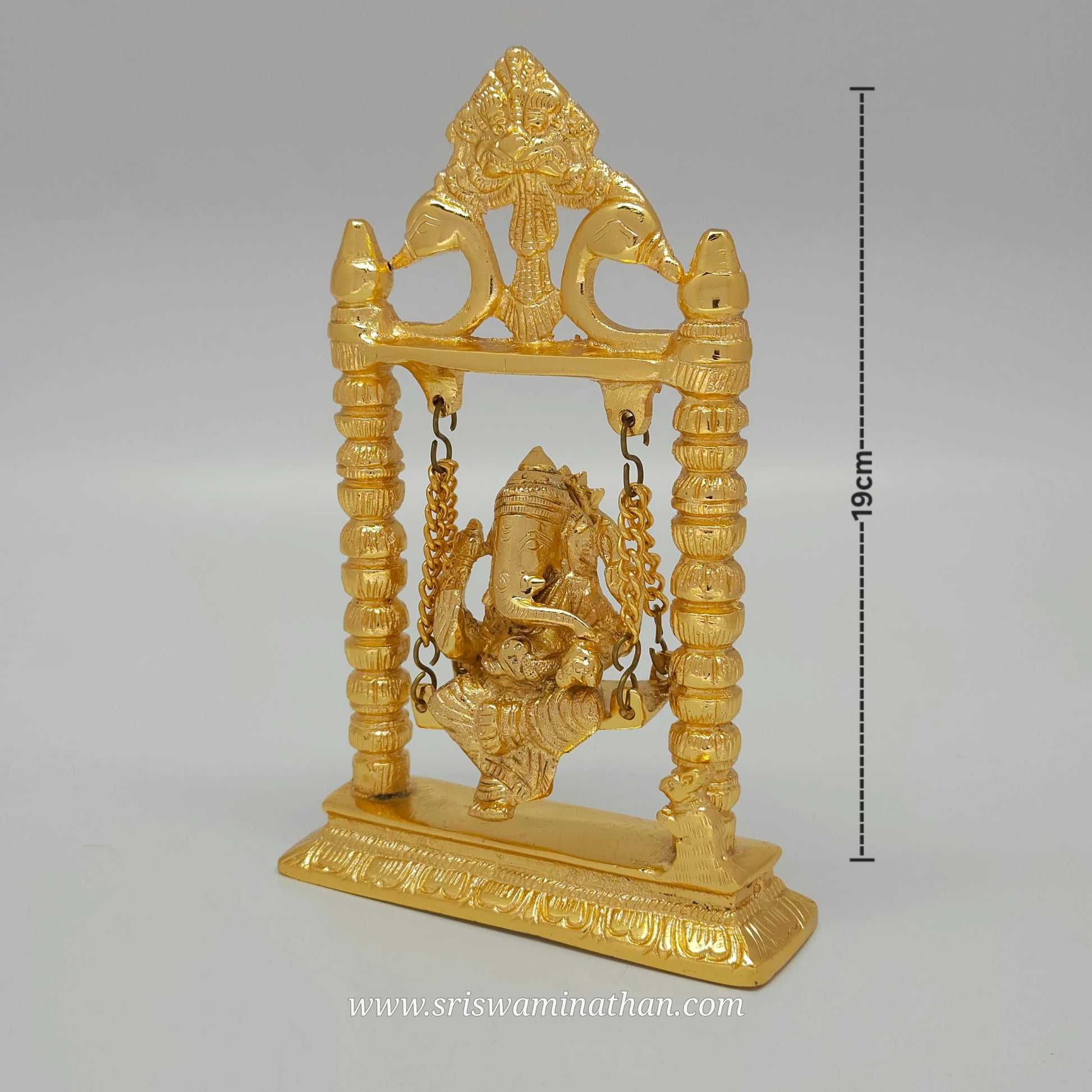 Side view of brass Ganesha statue seated on decorative swing