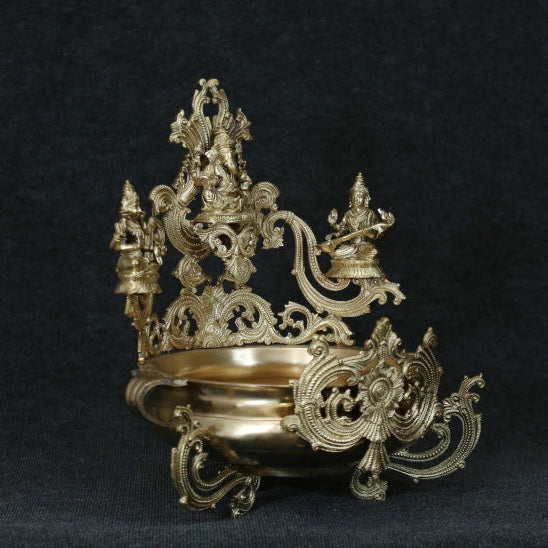 A 19 inch gold-colored statue of a Hindu goddess Lakshmi, Vinayagar and Saraswati with a lotus flower design on a dark background.