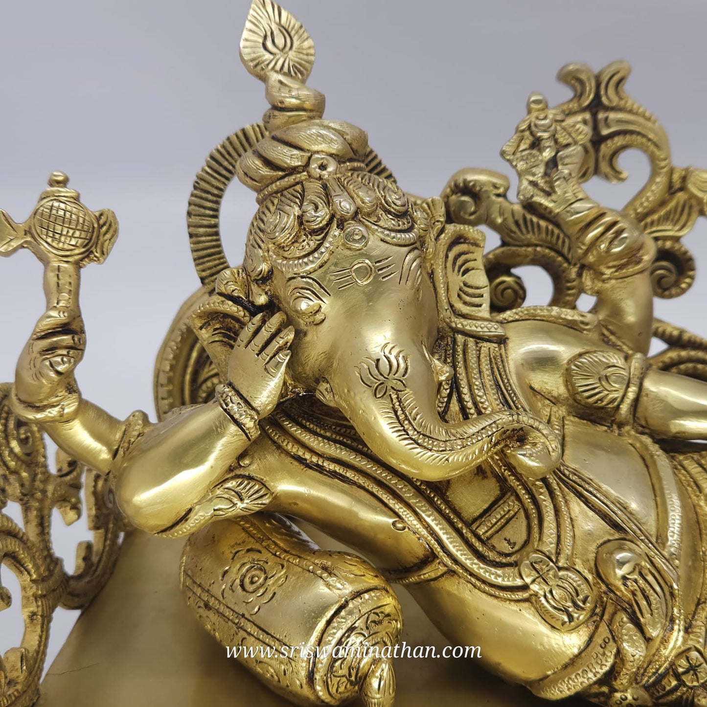 Gold-colored statue of a deity with intricate designs on a gray background