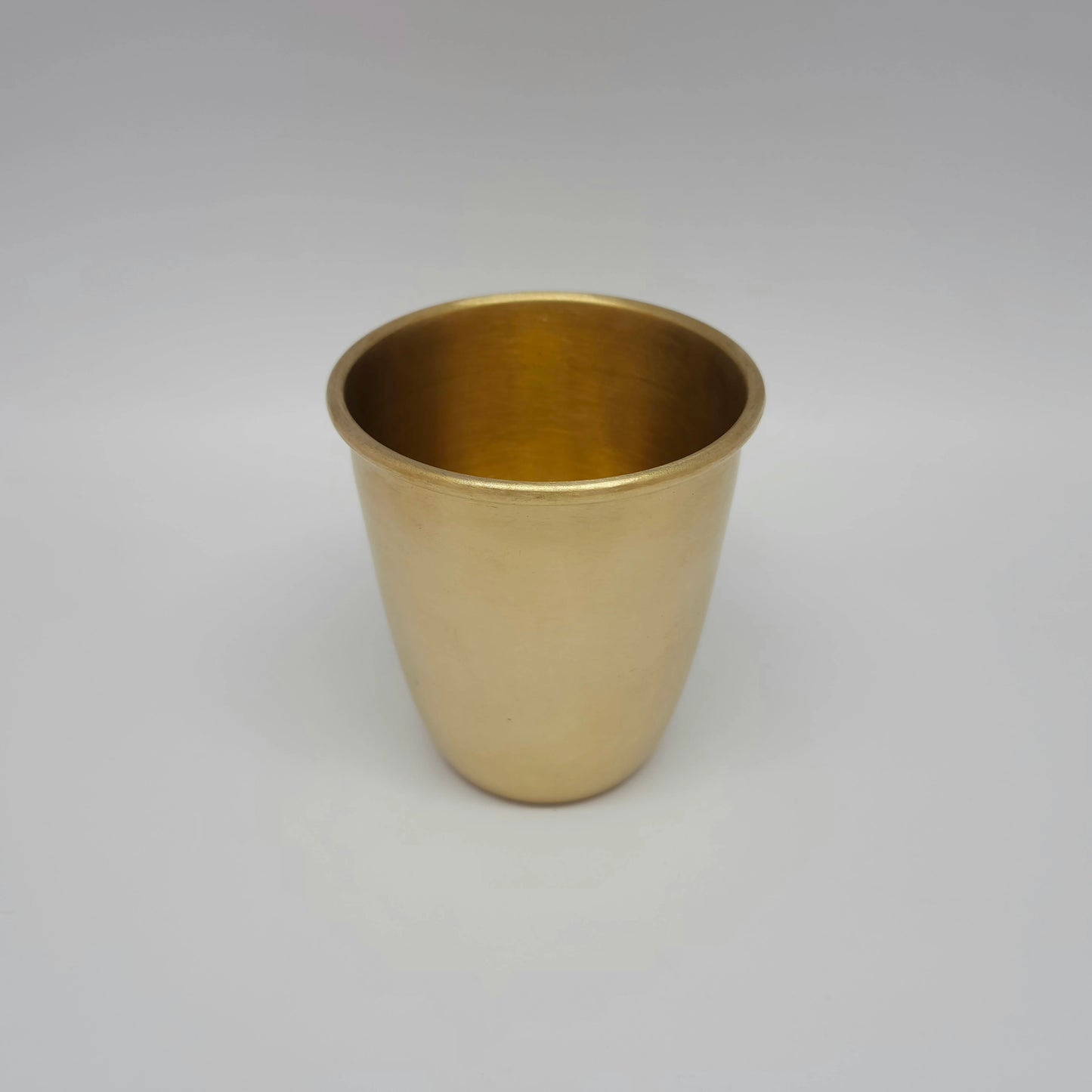 Slightly high angle view showing the smooth rim and 300ml capacity of the matte brass glass.