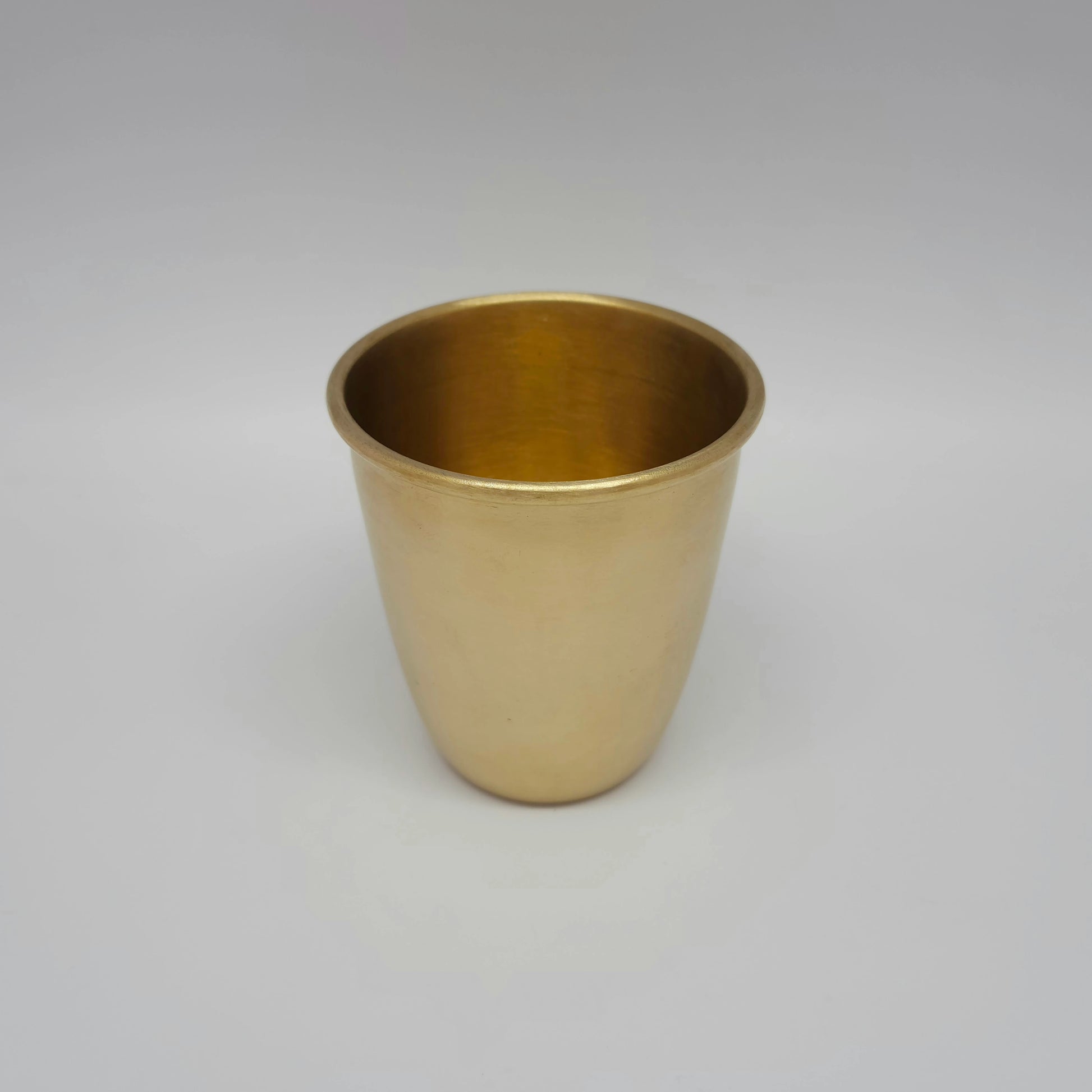 Slightly high angle view showing the smooth rim and 300ml capacity of the matte brass glass.