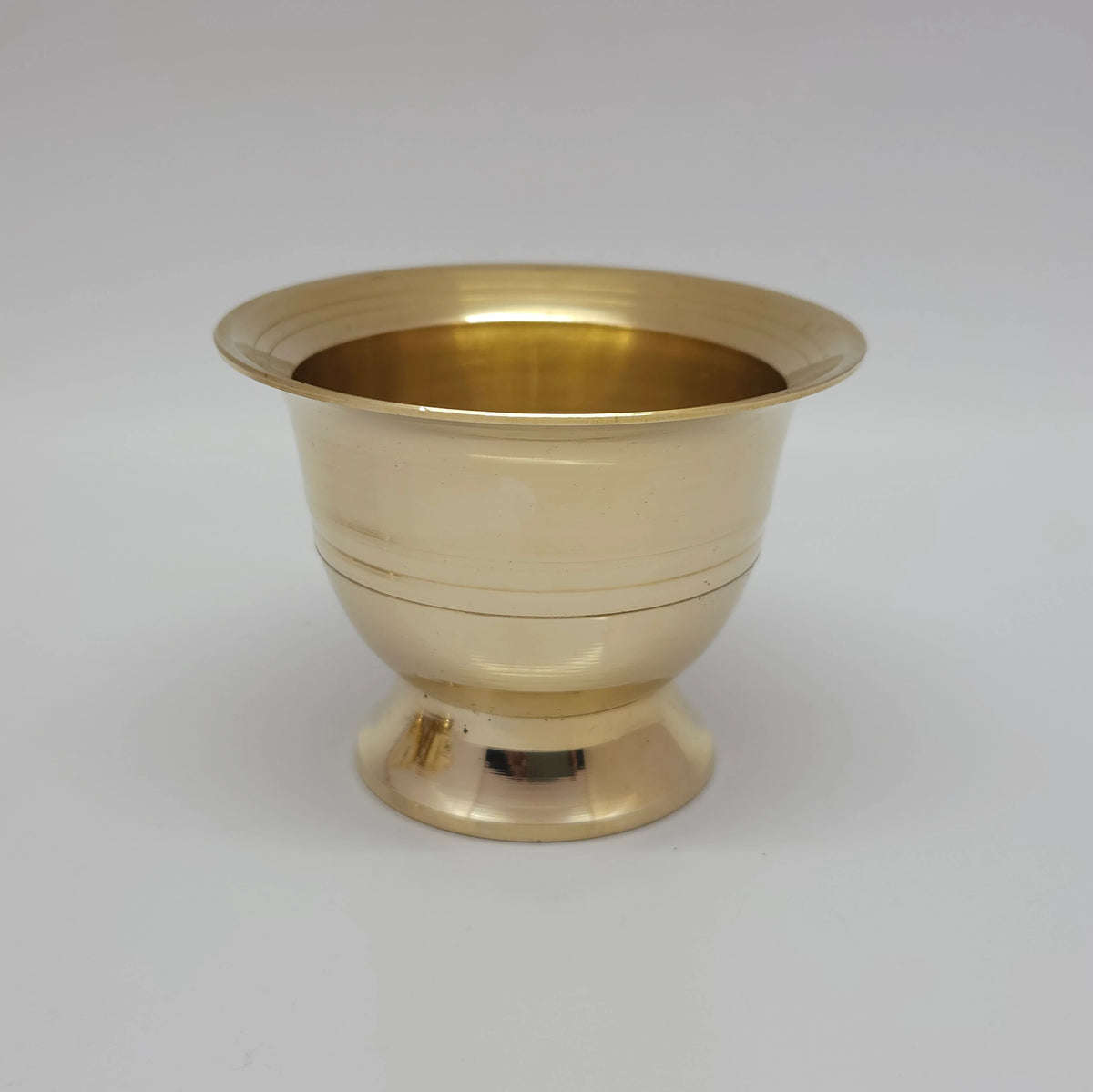 Close up front profile shot of a large size pure brass chandan pyali and gandham ginni cup highlighting the wide rim and pedestal base.