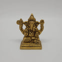 Straight close-up center shot of the antique finish brass Ganesha statue showcasing the detailed Trishula weapon, battle axe emblem, and seated Lalitasana posture.