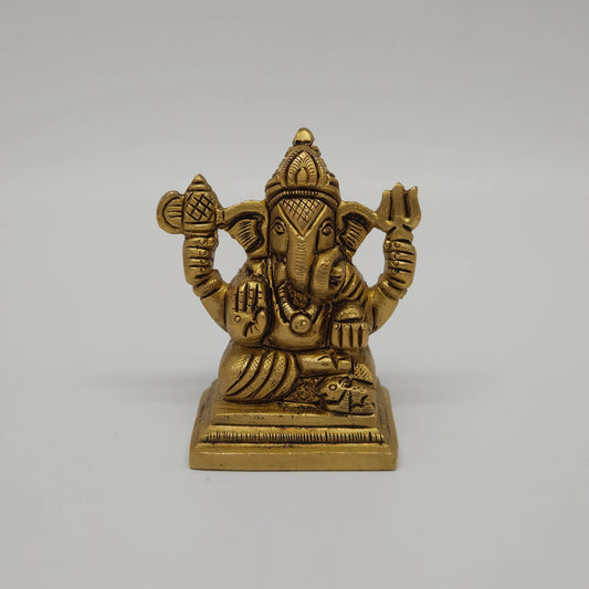 Straight close-up center shot of the antique finish brass Ganesha statue showcasing the detailed Trishula weapon, battle axe emblem, and seated Lalitasana posture.