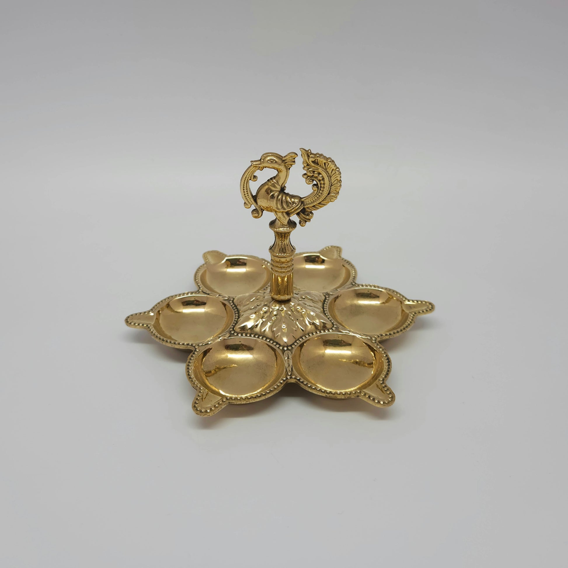 Front view showing a single brass multi-face peacock cluster lamp with individual oil cups.