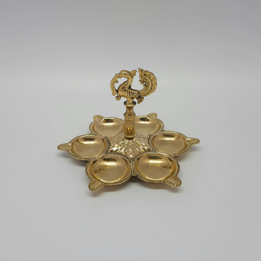 Front view showing a single brass multi-face peacock cluster lamp with individual oil cups.