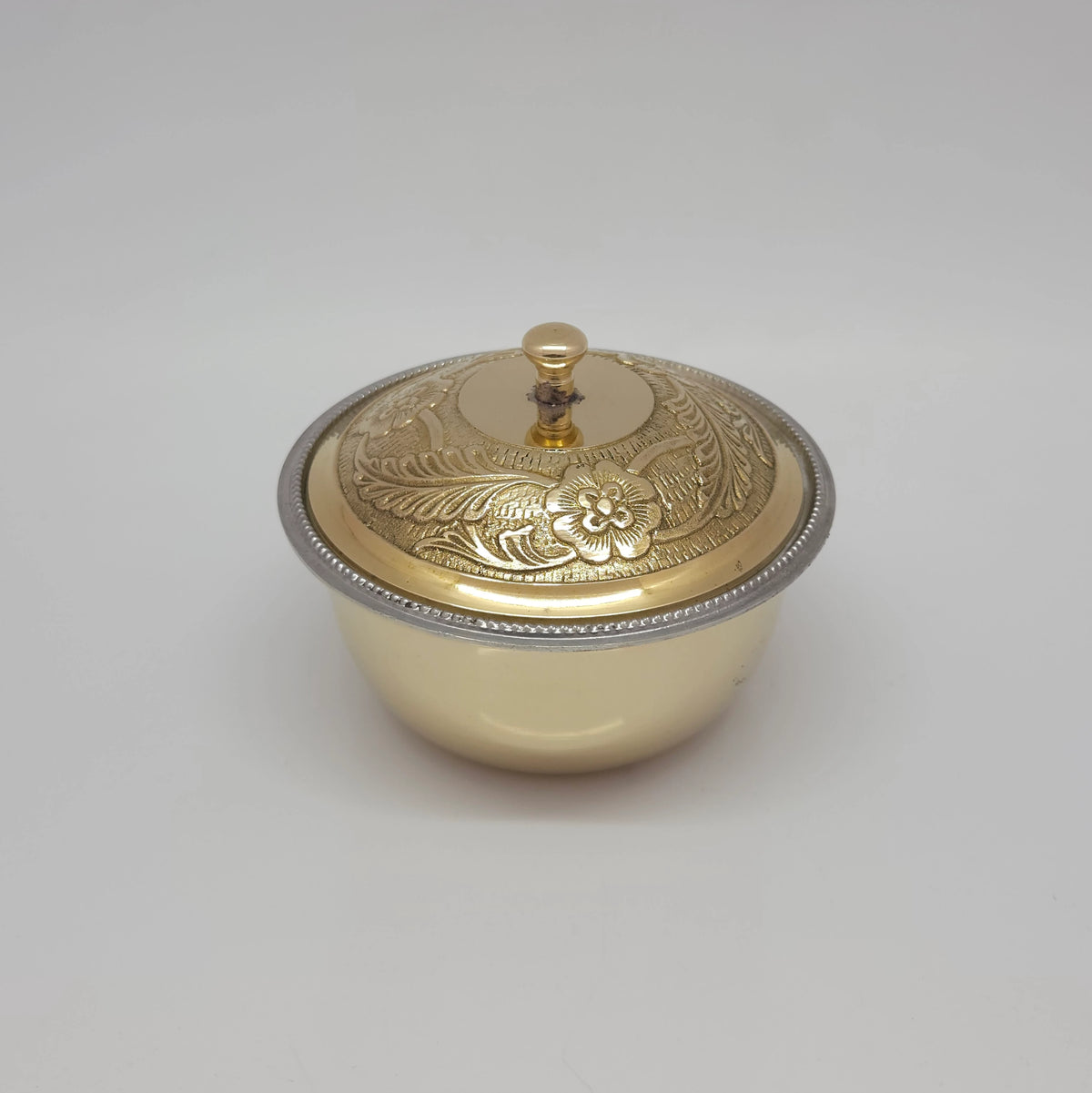 Front portrait view of the big size pure brass tin-lined uruli bowl with its matching hand-engraved floral patterned dome lid fully closed.