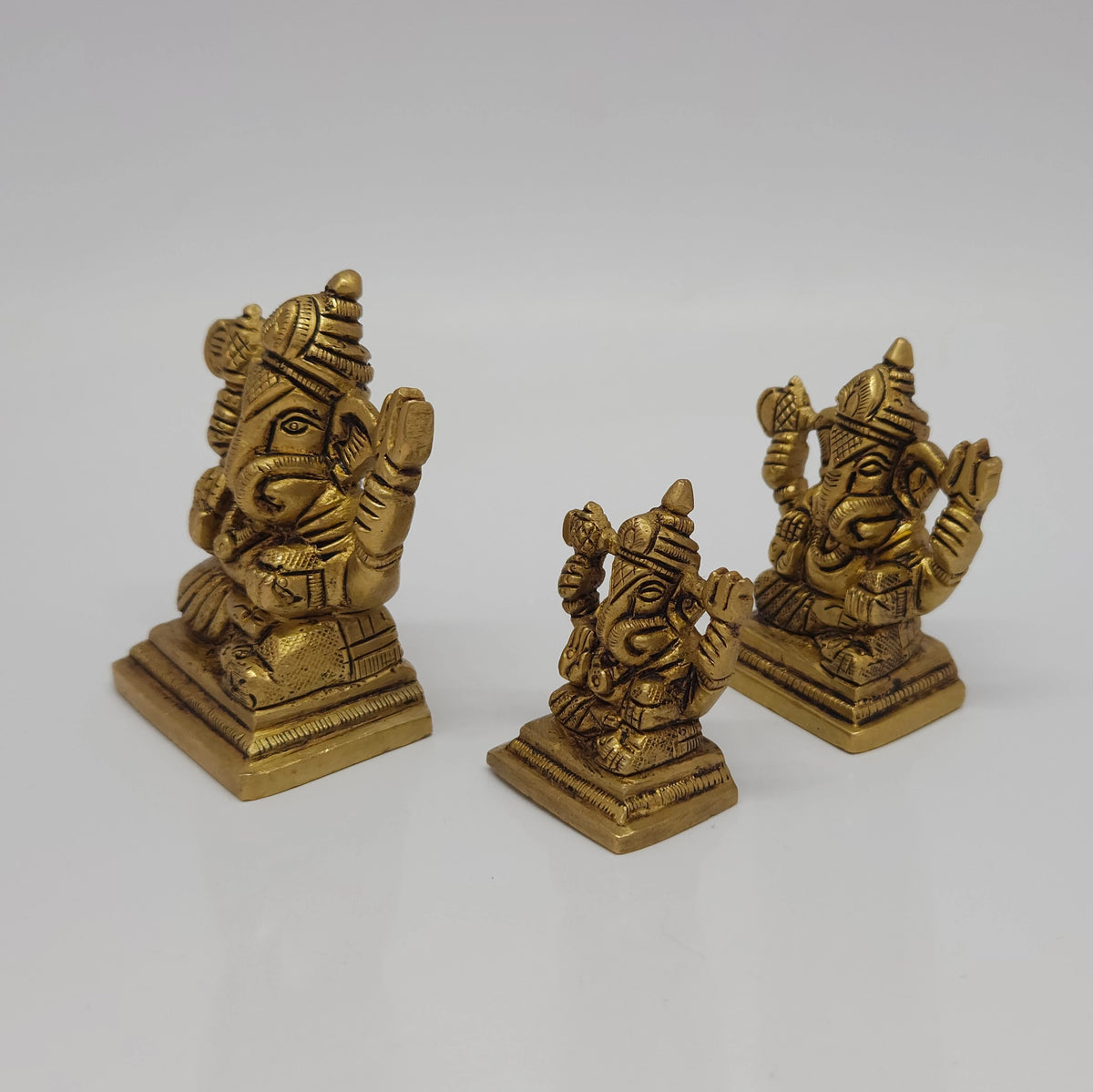 Three-quarter right perspective view of the brass Ganesha statue variations emphasizing the physical thickness of the casting and the distinct shape of the crowns.