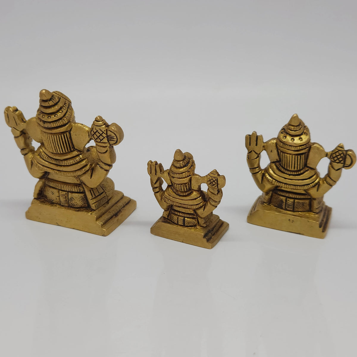Slightly high-angled studio shot of the antique gold finish Chaturbhuja Vinayagar statues displaying the overall depth and stable structural profiles of the square pedestals.