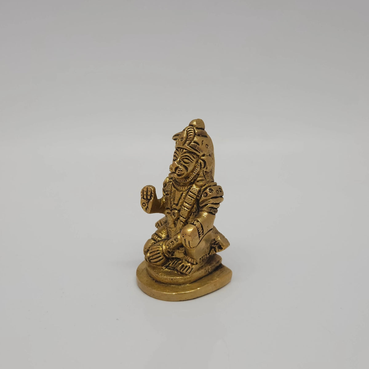 Three-quarter front left perspective view of the antique finish brass seated Hanuman idol highlighting the raised Abhaya Mudra palm and face details.
