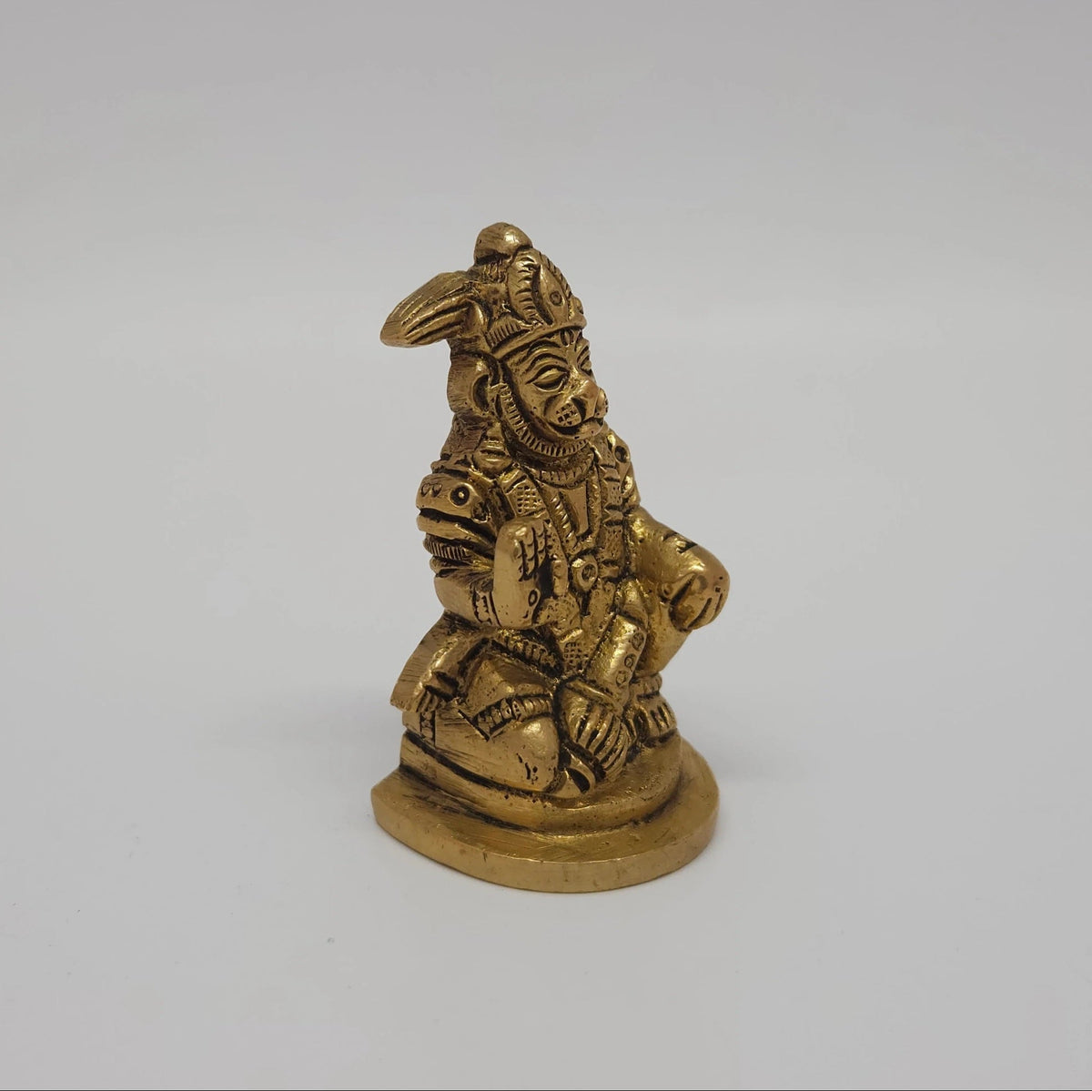 Three-quarter front right perspective view of the solid brass seated Hanuman statue focusing on the resting Gada placement beside his left leg.