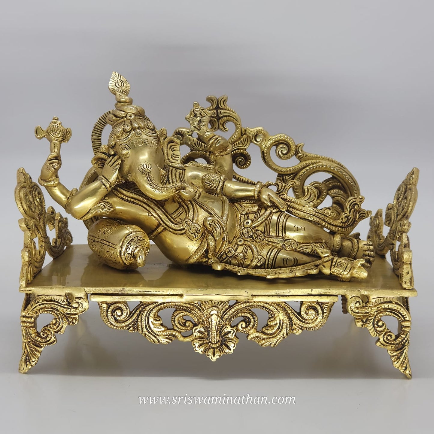 Decorative gold statue of a reclining figure on a gray background