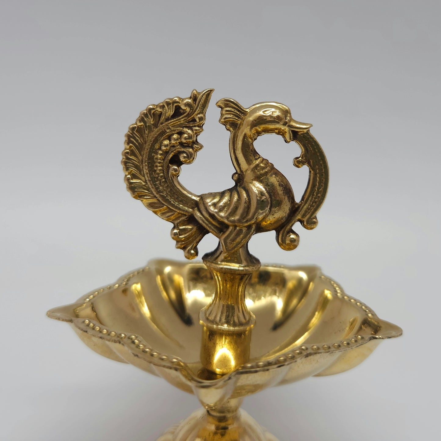 Close-up view showing the fine details of the handcrafted brass peacock and the 5-wick oil plate.