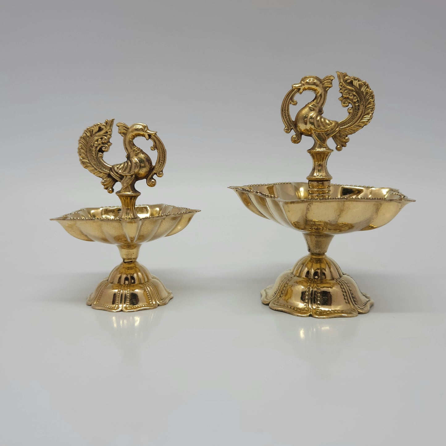 Two sizes of the pure brass peacock oil lamp shown from the front.