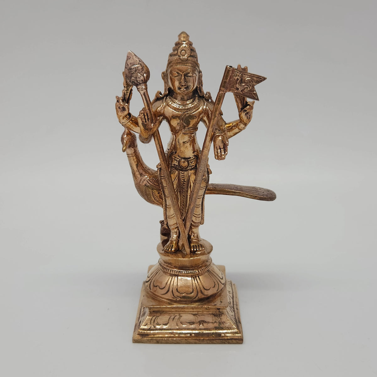 Front view of the standalone Lord Murugan Panchaloha idol with his divine peacock vehicle cast behind him on a square pedestal base.

