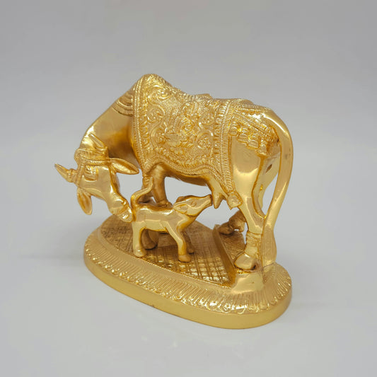 Three-quarter left perspective view of the solid brass Kamadhenu statue highlighting the oval pedestal base and detailed body contours.
