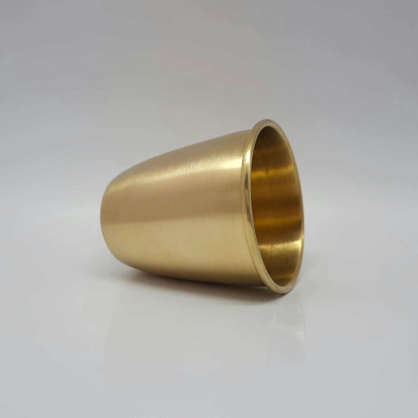 Side view of the thick matte finish brass water tumbler resting on a clear background to show base quality.