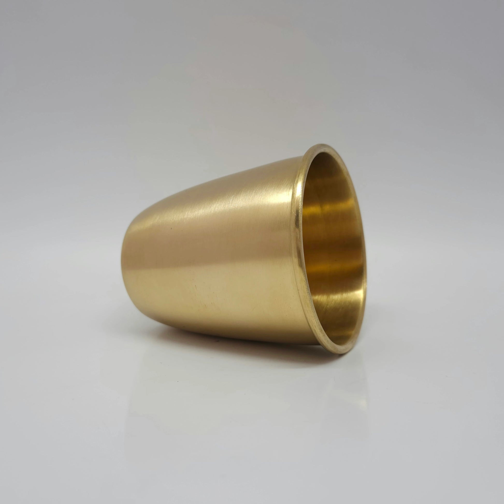 Side view of the thick matte finish brass water tumbler resting on a clear background to show base quality.