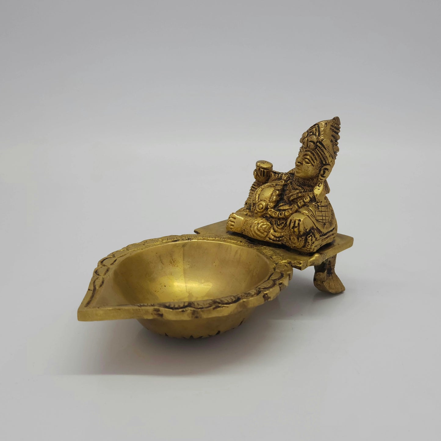 Front-left 45-degree angle profile view highlighting Kubera's sleeping pose stance on the pedestal with one leg visible and the lamp basin layout.