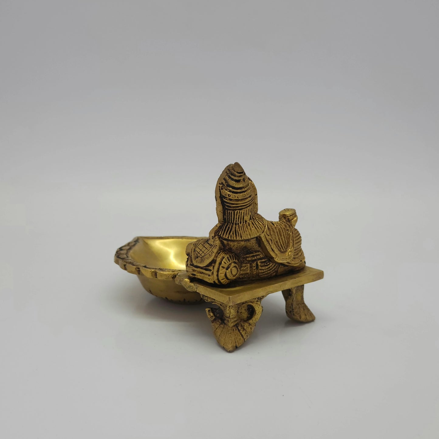Rear-left 45-degree perspective view showcasing the solid back structure of the deity, throne base details, and rich deep metal shadow lines
