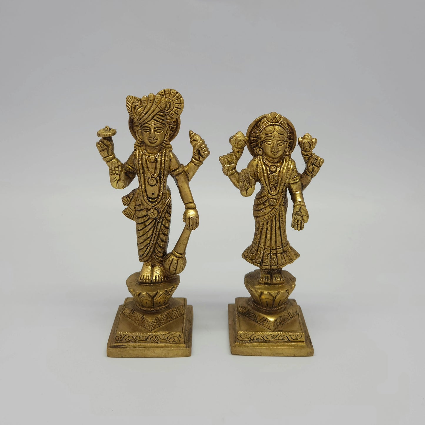 Flat straight front view of the 17cm high antique solid brass Lakshmi Narayana statue pair showing the matching tiered lotus pedestals