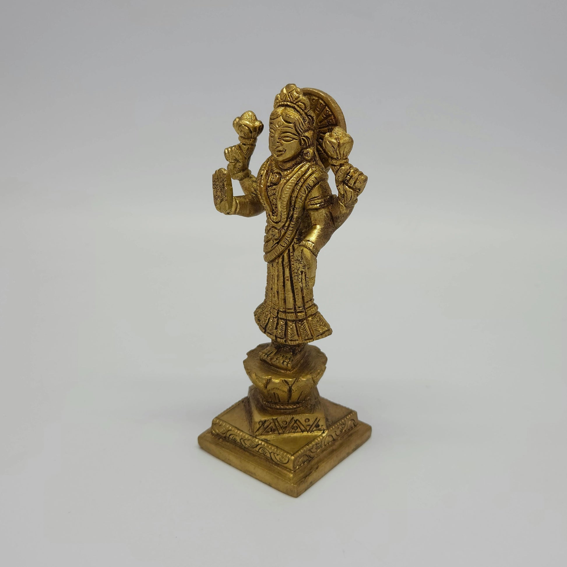 Solo left 45-degree angle view of the 16cm antique solid brass Goddess Lakshmi statue showcasing the blooming lotus stalk and fine traditional jewelry engravings.