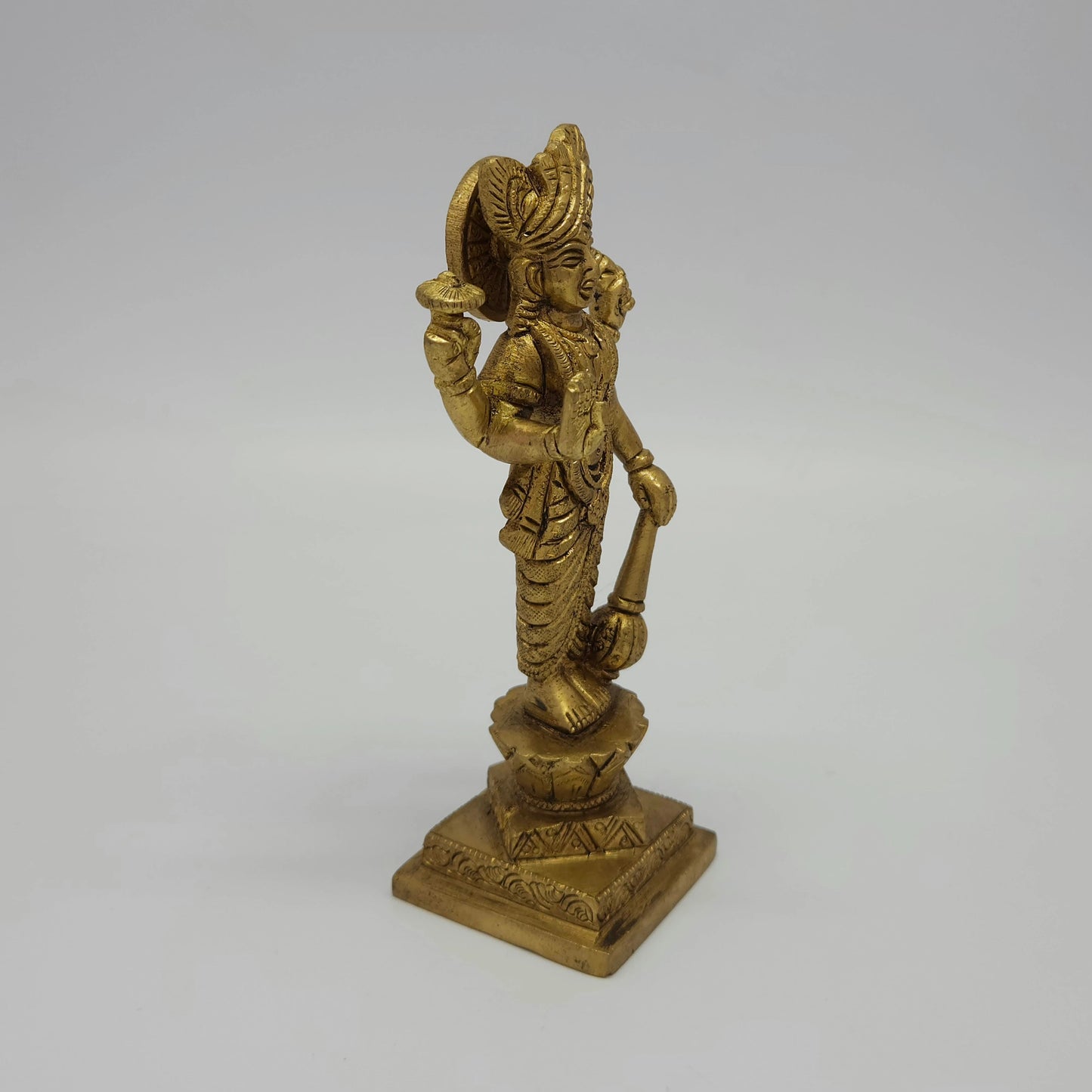 Solo right 45-degree angle close-up of the antique solid brass Lord Narayana idol emphasizing the hand-held Gada mace, Panchajanya Shankha, and base contours.