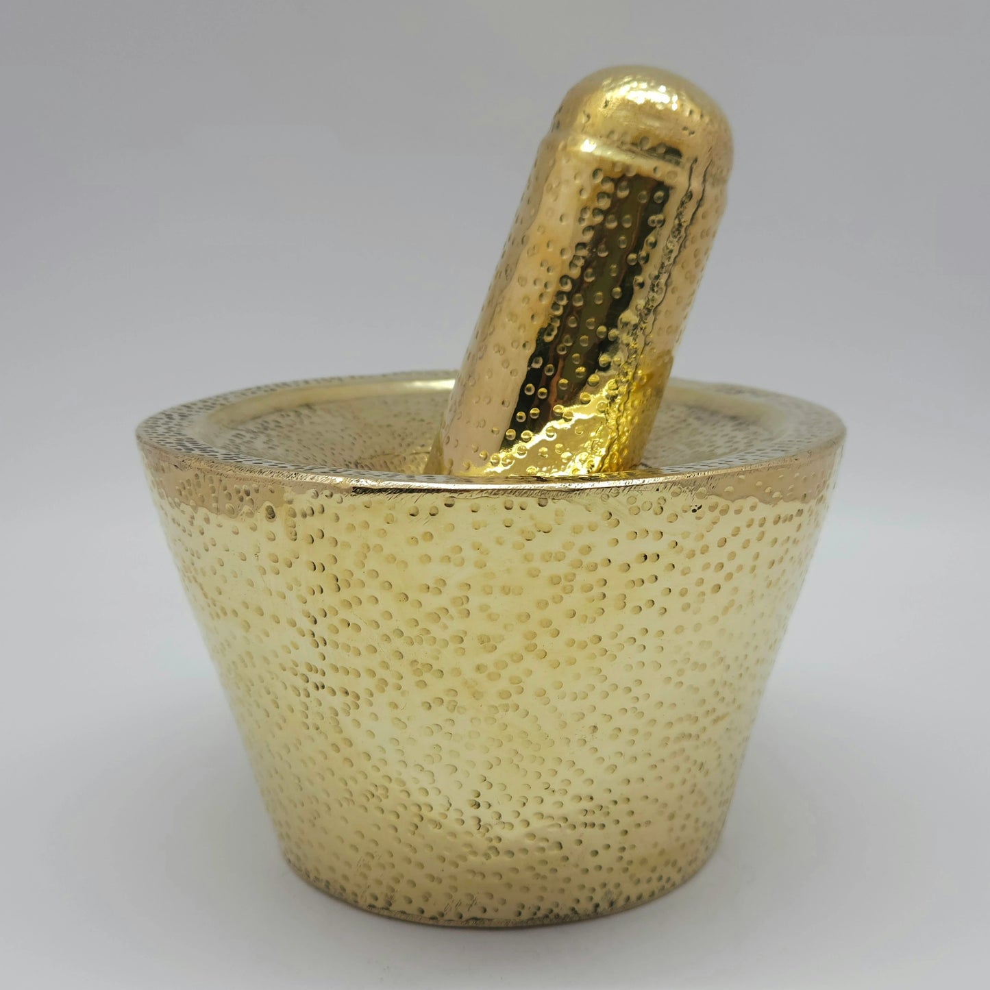 Flat straight front view showing the Kuzhavi muller resting inside the brass Aatukkal bowl for traditional marriage rituals
