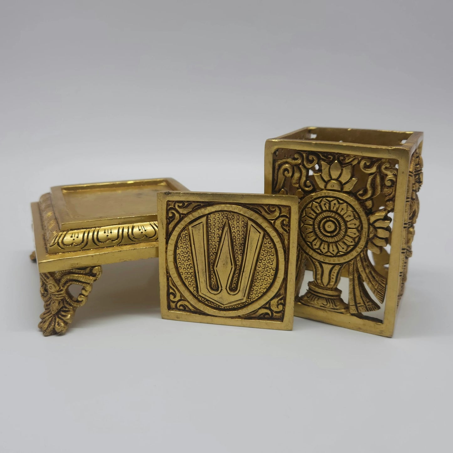Exploded component angle view showcasing the detachable lion-paw chowki stool pedestal, the openwork lattice cube container, and the removable namam top lid