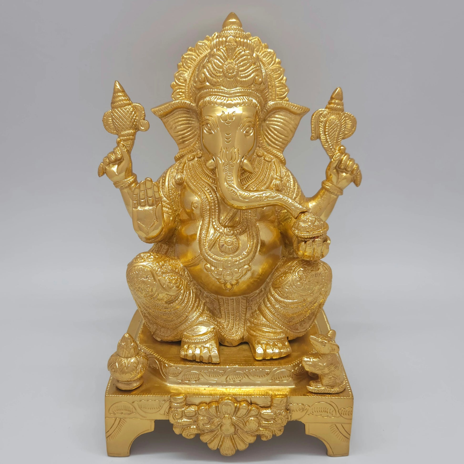 Flat straight front view of the 28cm premium high-gloss gold brass Ganesha statue on a flower-carved chowki for entrance decor.