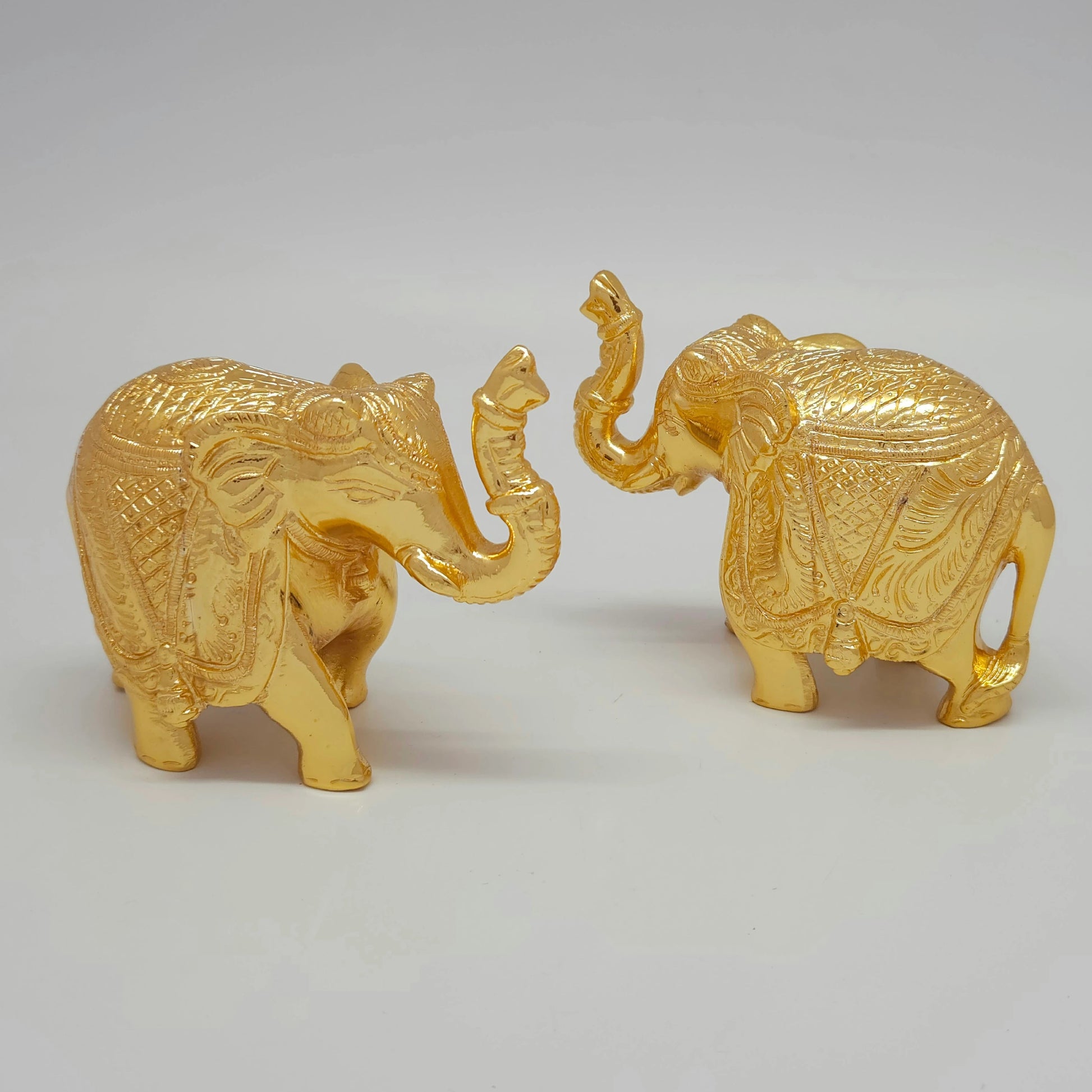 Diagonal procession view of the solid brass miniature elephant pair set highlighting the contrast between the raised and arched trunks