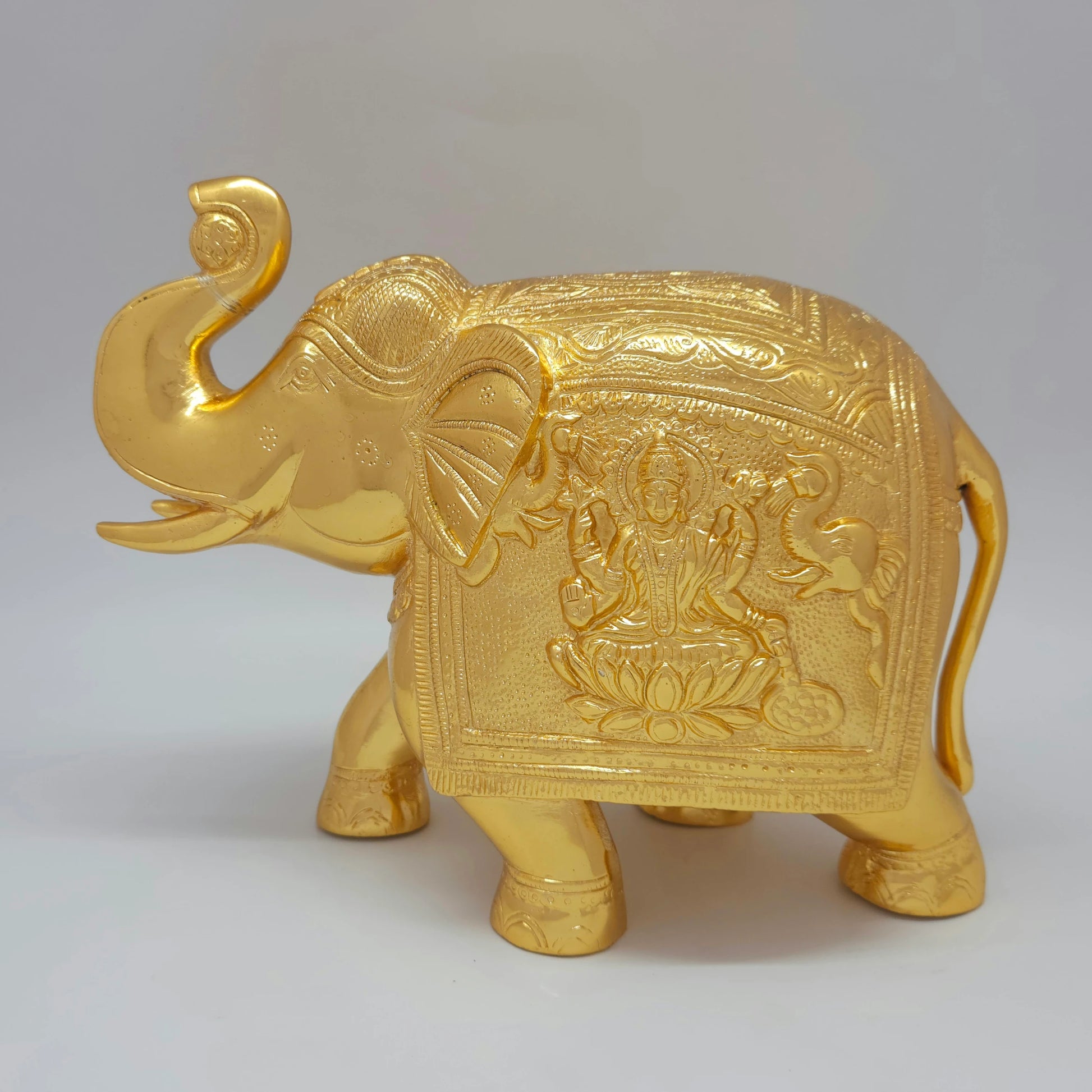 Flat left pose profile view of the 21cm premium solid brass elephant statue showing the Gaja-Lakshmi engraving with two showering elephants on the saddle cloth.
