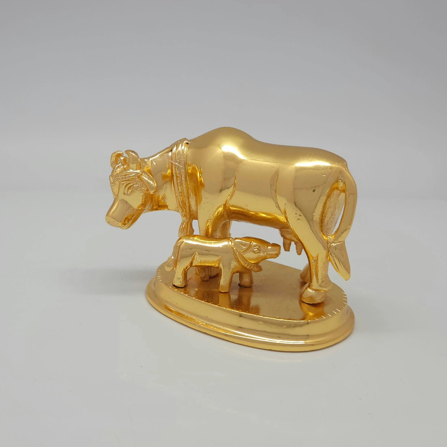 Front-left 45-degree angle profile view highlighting the feeding calf, chiseled neck bell hanging detail, and polished metal muscle highlights