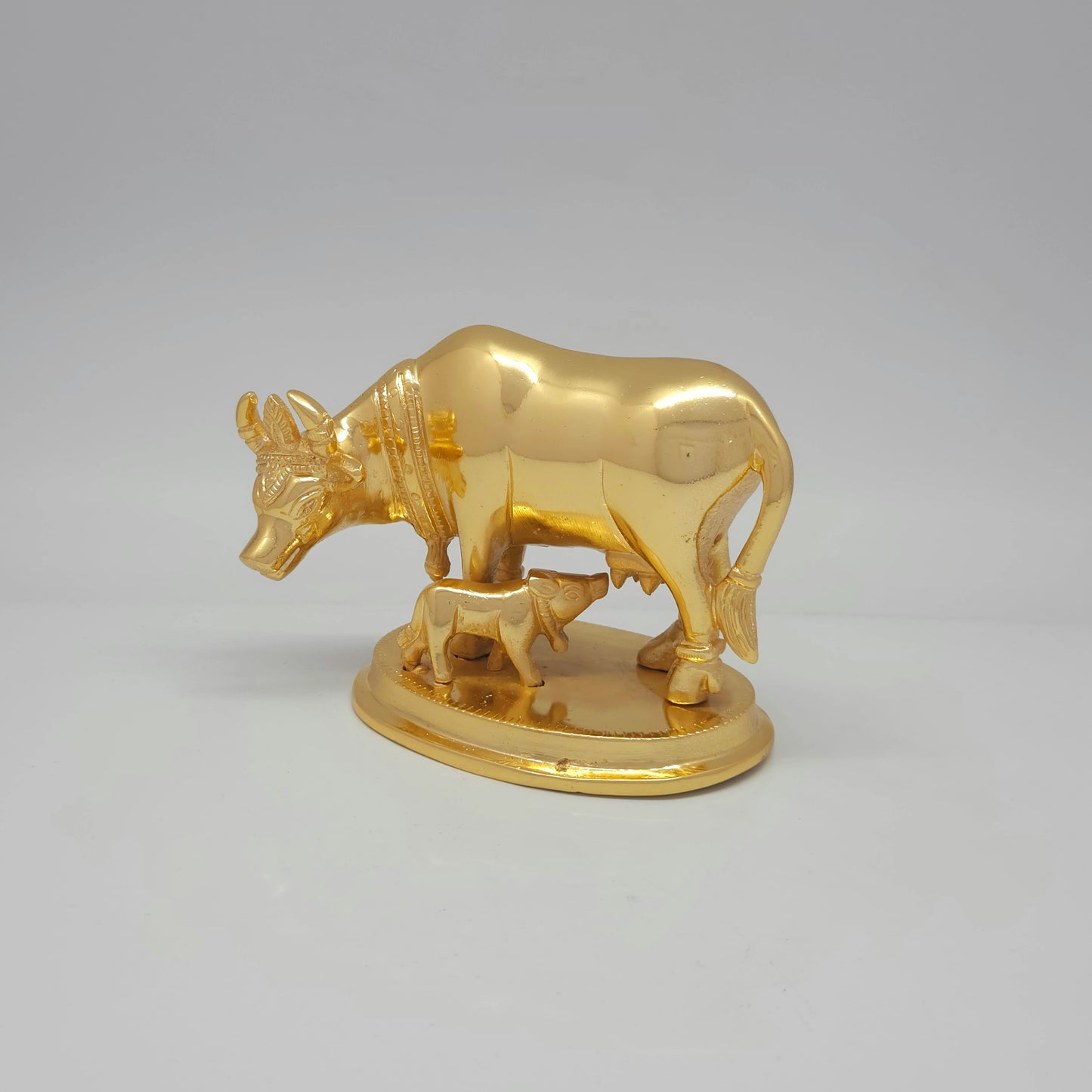 Front-left 45-degree angle profile view highlighting the feeding calf, chiseled neck bell hanging detail, and polished metal muscle highlights.