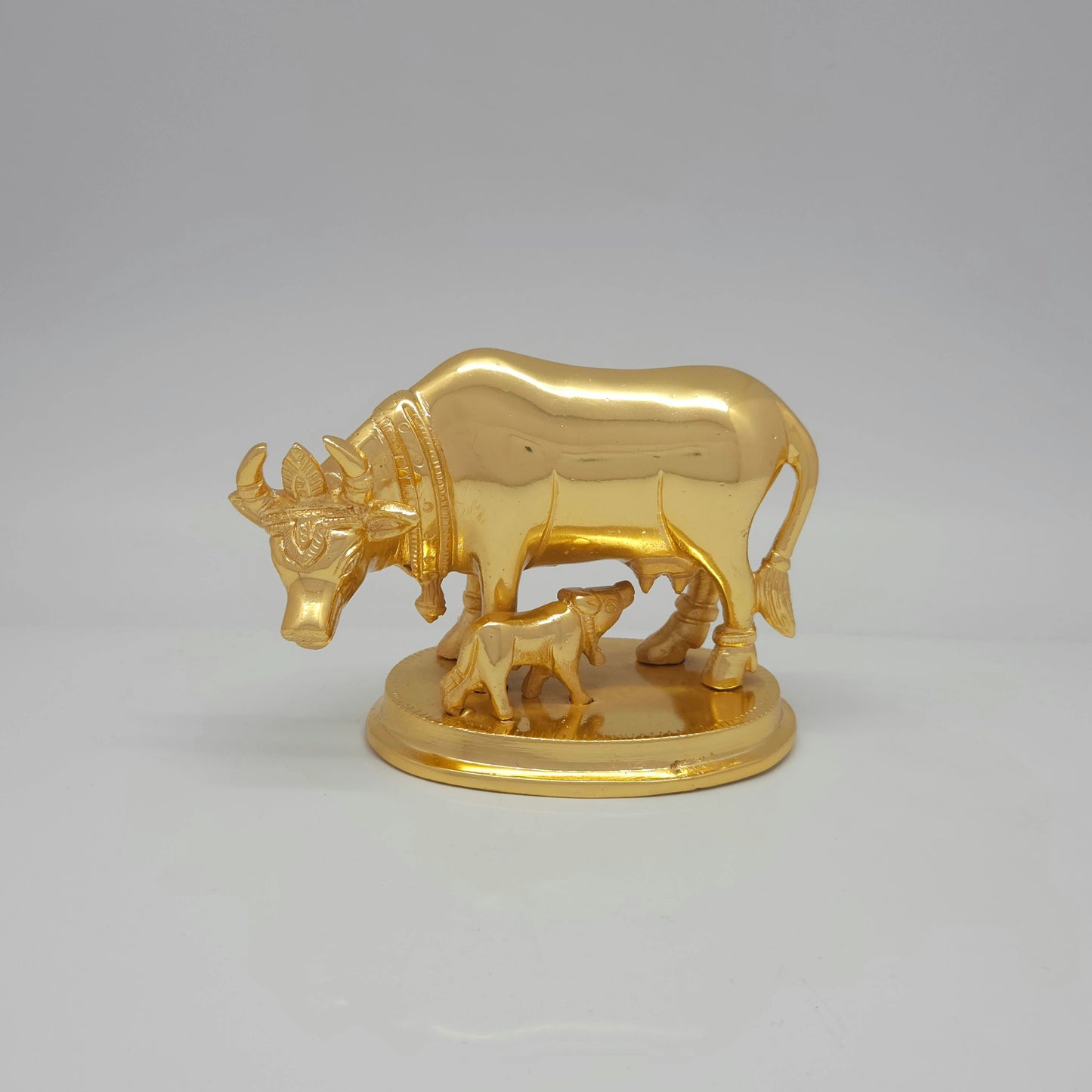 Flat straight level front view at a exact 0-degree angle highlighting the horizontal body lines, matching base steps, and symmetrical facial contours of the solid brass Kamadhenu sculpture.