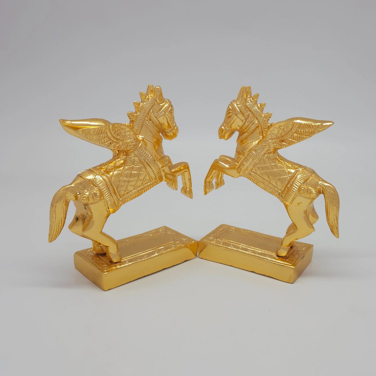 45-Degree Rear perspective of the paired solid brass Pegasus sculptures highlighting the wing feathers and flowing tail textures.