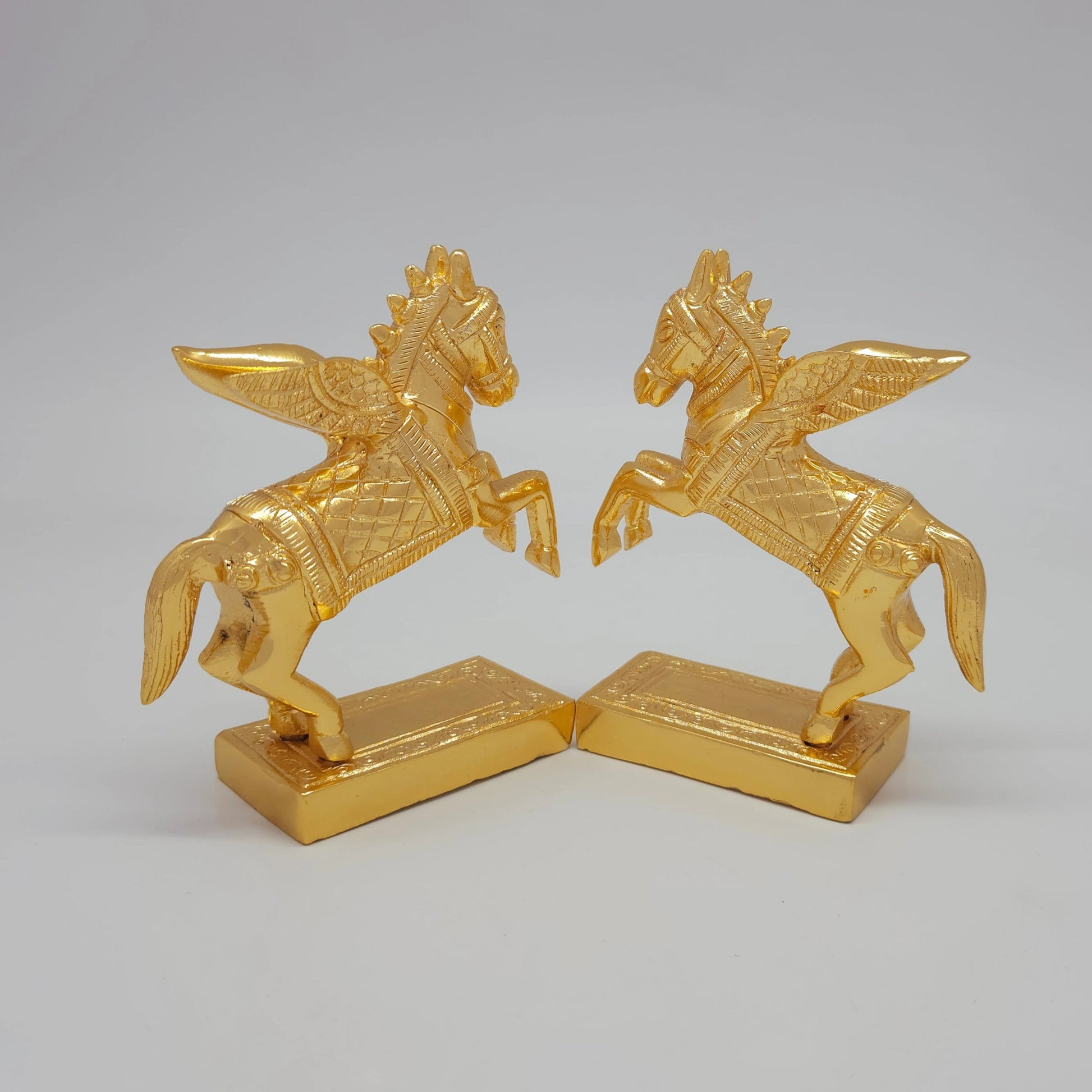 45-Degree Rear perspective of the paired solid brass Pegasus sculptures highlighting the wing feathers and flowing tail textures.