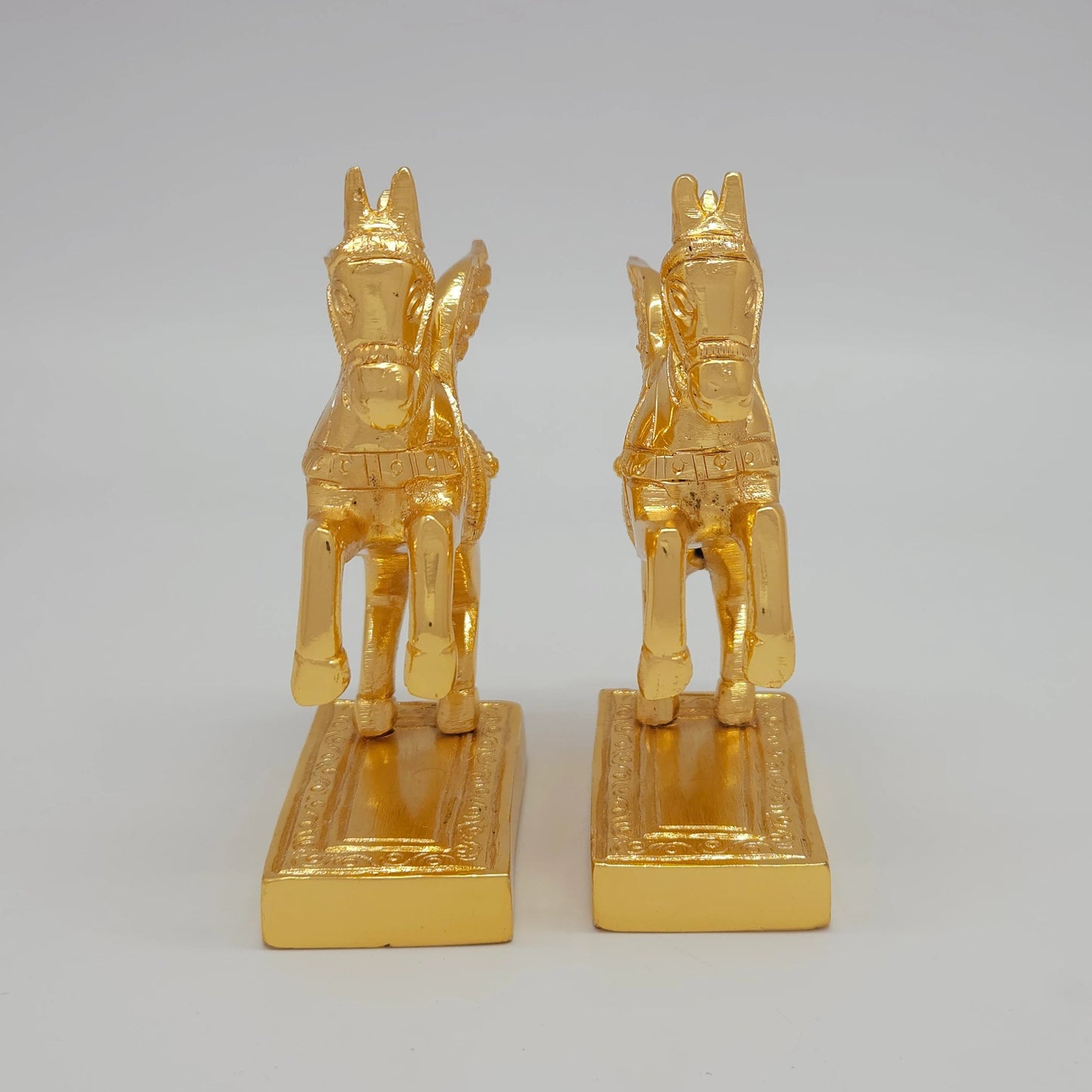 close-up emphasizing the rearing front hooves and the thick solid block base layout of the paired metal ornaments.